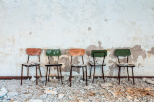 five small chairs side by side in an old abandoned building, rubble and dust, peeling wall five small chairs side by side in an old abandoned building, rubble and dust, peeling wall