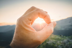 Man hand circling the sun with with fingers at sunrise Man hand circling the sun with with fingers at sunrise
