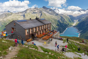 Hikers at Olperer refuge with Lake Schlegeispeicher on the background, Zillertal Alps, Tyrol, Schwaz district, Austria Hikers at Olperer refuge with Lake Schlegeispeicher on the background, Zillertal Alps, Tyrol, Schwaz district, Austria
