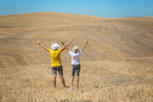 mom and daughter with arms raised to the sky in val d'orcia, summer scene, Castiglione d'Orcia, province of Siena, Tuscany, Italy mom and daughter with arms raised to the sky in val d'orcia, summer scene, Castiglione d'Orcia, province of Siena, Tuscany, Italy