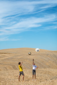 mother and daughter play with their hats in a field in Val d'Orcia, Castiglione d'Orcia, province of Siena, Tuscany, Italy mother and daughter play with their hats in a field in Val d'Orcia, Castiglione d'Orcia, province of Siena, Tuscany, Italy