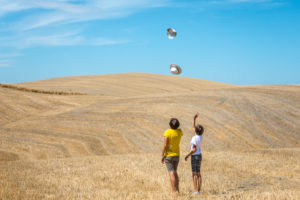mother and daughter play with their hats in a field in Val d'Orcia, Castiglione d'Orcia, province of Siena, Tuscany, Italy mother and daughter play with their hats in a field in Val d'Orcia, Castiglione d'Orcia, province of Siena, Tuscany, Italy