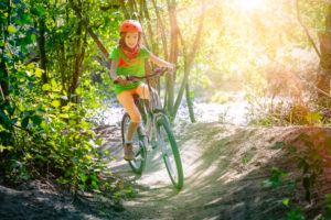 Italy, Veneto, Belluno, Agordino, little girl ( 10 years old) has fun with her bicycle along a forest path Italy, Veneto, Belluno, Agordino, little girl ( 10 years old) has fun with her bicycle along a forest path