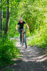 Italy, Veneto, Belluno, Agordino, woman cyclist (45 years old) with an e-bike on a dirt road in the woods Italy, Veneto, Belluno, Agordino, woman cyclist (45 years old) with an e-bike on a dirt road in the woods