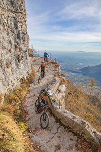 Group of e-mountain bikers riding along the Granatiere Trail on Monte Cengio, Vicenza Province, Veneto, Italy