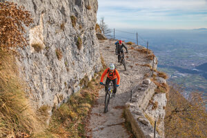Group of e-mountain bikers riding along the Granatiere Trail on Monte Cengio, Vicenza Province, Veneto, Italy
