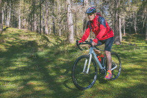 Cyclist riding an e-gravel bike through an alpine forest trail during spring, Anterivo, Autonomous Province of Bolzano, South Tyrol, Italy