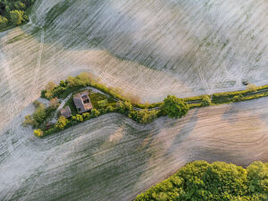 Aerial view of a cultivated field and abandoned farmhouse in the rural landscape of Cesane Park, near Urbino, Marche region, central Italy