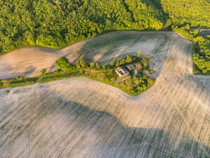Aerial view of a cultivated field and abandoned farmhouse in the rural landscape of Cesane Park, near Urbino, Marche region, central Italy