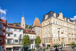 Medieval Torre delle Dodici (Zwölferturm) rising among historic and elegant buildings in the old town of Merano, with the bell tower of St. Nicholas Church in the background. Merano, South Tyrol, Trentino-Alto Adige, northern Italy