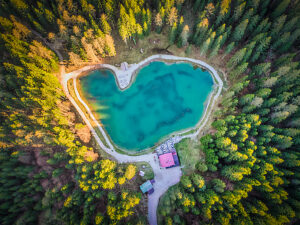Aerial view of Lago Pianozes, a small alpine lake surrounded by dense conifer forest near Cortina d'Ampezzo, Dolomites, Belluno province, Veneto region, northeastern Italy