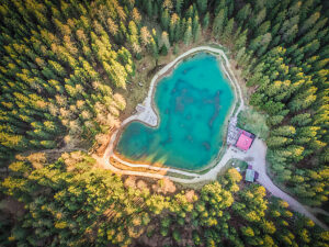 Aerial view of Lago Pianozes, a small alpine lake surrounded by dense conifer forest near Cortina d'Ampezzo, Dolomites, Belluno province, Veneto region, northeastern Italy