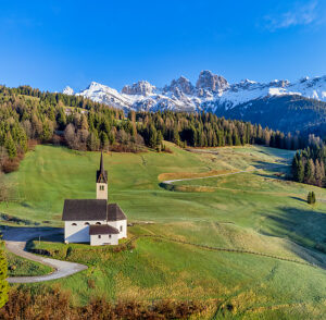 Aerial view of the Church of the Beata Vergine della Salute on the hill overlooking the village of Caviola, in the background the Cime díAuta, Biois valley, Falcade, Belluno province, Veneto region, northeastern Italy