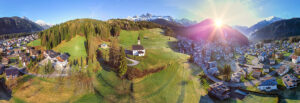Aerial view of the Church of the Beata Vergine della Salute on the hill overlooking the village of Caviola, with its rooftops and houses nestled among alpine meadows and forest. Valle del Biois, Falcade, Belluno province, Veneto region, northeastern Italy