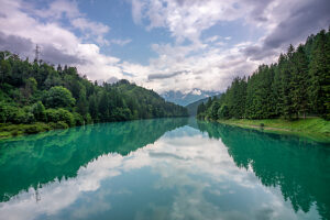 Centro Cadore Lake after spring rain, with cloudy skies and forested Alpine peaks. Domegge di Cadore, Belluno province, Veneto, northern Italy