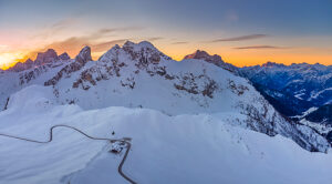 Aerial winter view over Passo Giau with Monte Cernera in the center, Monte Pelmo in the background to the left, and Monte Civetta to the right. The winding pass road and a mountain refuge are visible among the snow-covered alpine slopes. Dolomites, Colle Santa Lucia municipality, Belluno province, Veneto region, Italy
