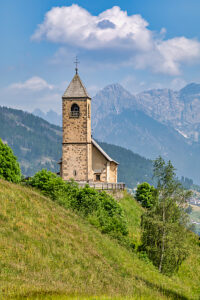 The Church of San Leonardo Vecchio, a unique Gothic-medieval architectural gem built in the mid-1500s by Nicolo Roupel, stands peacefully in Casamazzagno, Comelico Superiore, with the Dolomites towering in the background ñ Belluno Province, Veneto, Italy
