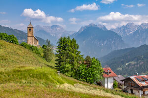 The Church of San Leonardo Vecchio, a unique Gothic-medieval architectural gem built in the mid-1500s by Nicolo Roupel, stands peacefully in Casamazzagno, Comelico Superiore, with the Dolomites towering in the background ñ Belluno Province, Veneto, Italy