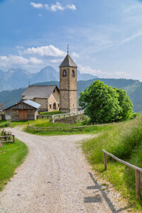 The Church of San Leonardo Vecchio, a unique Gothic-medieval architectural gem built in the mid-1500s by Nicolo Roupel, stands peacefully in Casamazzagno, Comelico Superiore, with the Dolomites towering in the background ñ Belluno Province, Veneto, Italy