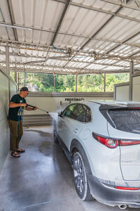 A man washing his SUV/crossover with a high-pressure jet at a self-service coin-operated car wash A man washing his SUV/crossover with a high-pressure jet at a self-service coin-operated car wash