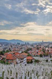 Kovaci Cemetery with white tombstones in the foreground and panoramic view of Sarajevo under dramatic cloudy sky, Bosnia and Herzegovina Kovaci Cemetery with white tombstones in the foreground and panoramic view of Sarajevo under dramatic cloudy sky, Bosnia and Herzegovina