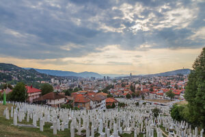 Kovaci Cemetery with white tombstones in the foreground and panoramic view of Sarajevo under dramatic cloudy sky, Bosnia and Herzegovina Kovaci Cemetery with white tombstones in the foreground and panoramic view of Sarajevo under dramatic cloudy sky, Bosnia and Herzegovina
