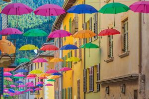 Colorful umbrellas suspended above the narrow streets of Castello Tesino, creating a lively and artistic summer atmosphere in this Trentino mountain village. Autonomous Province of Trento, Trentino, Italy Colorful umbrellas suspended above the narrow streets of Castello Tesino, creating a lively and artistic summer atmosphere in this Trentino mountain village. Autonomous Province of Trento, Trentino, Italy