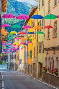 Colorful umbrellas suspended above the narrow streets of Castello Tesino, creating a lively and artistic summer atmosphere in this Trentino mountain village. Autonomous Province of Trento, Trentino, Italy Colorful umbrellas suspended above the narrow streets of Castello Tesino, creating a lively and artistic summer atmosphere in this Trentino mountain village. Autonomous Province of Trento, Trentino, Italy