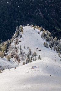 Light and shadow play over the snowy slopes above Penia, a hamlet of Canazei in Val di Fassa, early autumn snow dusts the larch trees and alpine huts, autonomous Province of Trento, Trentino-Alto Adige, Italy Light and shadow play over the snowy slopes above Penia, a hamlet of Canazei in Val di Fassa, early autumn snow dusts the larch trees and alpine huts, autonomous Province of Trento, Trentino-Alto Adige, Italy