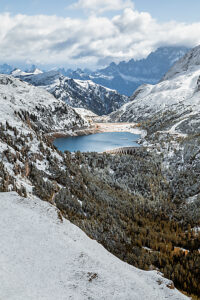 Elevated view of Lake Fedaia and its dam on the Trentino side of Fedaia Pass with Mount Civetta in the background under autumn snow. Canazei, Trentino-Alto Adige, Italy Elevated view of Lake Fedaia and its dam on the Trentino side of Fedaia Pass with Mount Civetta in the background under autumn snow. Canazei, Trentino-Alto Adige, Italy