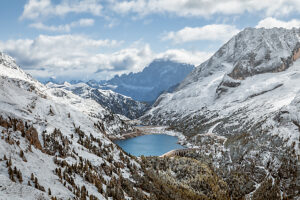 Elevated view of Lake Fedaia and its dam on the Trentino side of Fedaia Pass with Mount Civetta in the background under autumn snow. Canazei, Trentino-Alto Adige, Italy Elevated view of Lake Fedaia and its dam on the Trentino side of Fedaia Pass with Mount Civetta in the background under autumn snow. Canazei, Trentino-Alto Adige, Italy