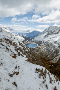 Elevated view of Lake Fedaia and its dam on the Trentino side of Fedaia Pass with Mount Civetta in the background under autumn snow. Canazei, Trentino-Alto Adige, Italy Elevated view of Lake Fedaia and its dam on the Trentino side of Fedaia Pass with Mount Civetta in the background under autumn snow. Canazei, Trentino-Alto Adige, Italy