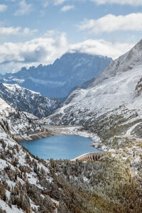 Elevated view of Lake Fedaia and its dam on the Trentino side of Fedaia Pass with Mount Civetta in the background under autumn snow. Canazei, Trentino-Alto Adige, Italy Elevated view of Lake Fedaia and its dam on the Trentino side of Fedaia Pass with Mount Civetta in the background under autumn snow. Canazei, Trentino-Alto Adige, Italy