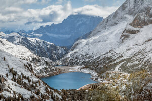 Elevated view of Lake Fedaia and its dam on the Trentino side of Fedaia Pass with Mount Civetta in the background under autumn snow. Canazei, Trentino-Alto Adige, Italy Elevated view of Lake Fedaia and its dam on the Trentino side of Fedaia Pass with Mount Civetta in the background under autumn snow. Canazei, Trentino-Alto Adige, Italy