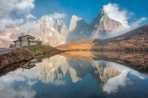 The iconic Baita Segantini reflected in the still waters at sunset with the Pale di San Martino peaks glowing in the evening light. Primiero San Martino di Castrozza, Trento province, Trentino, Italy The iconic Baita Segantini reflected in the still waters at sunset with the Pale di San Martino peaks glowing in the evening light. Primiero San Martino di Castrozza, Trento province, Trentino, Italy