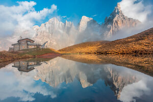 The iconic Baita Segantini reflected in the still waters at sunset with the Pale di San Martino peaks glowing in the evening light. Primiero San Martino di Castrozza, Trento province, Trentino, Italy The iconic Baita Segantini reflected in the still waters at sunset with the Pale di San Martino peaks glowing in the evening light. Primiero San Martino di Castrozza, Trento province, Trentino, Italy