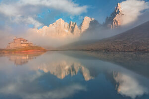 The iconic Baita Segantini reflected in the still waters at sunset with the Pale di San Martino peaks glowing in the evening light. Primiero San Martino di Castrozza, Trento province, Trentino, Italy The iconic Baita Segantini reflected in the still waters at sunset with the Pale di San Martino peaks glowing in the evening light. Primiero San Martino di Castrozza, Trento province, Trentino, Italy