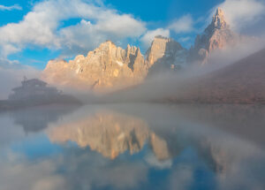 The iconic Baita Segantini reflected in the still waters at sunset with the Pale di San Martino peaks glowing in the evening light. Primiero San Martino di Castrozza, Trento province, Trentino, Italy The iconic Baita Segantini reflected in the still waters at sunset with the Pale di San Martino peaks glowing in the evening light. Primiero San Martino di Castrozza, Trento province, Trentino, Italy