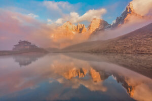 The iconic Baita Segantini reflected in the still waters at sunset with the Pale di San Martino peaks glowing in the evening light. Primiero San Martino di Castrozza, Trento province, Trentino, Italy The iconic Baita Segantini reflected in the still waters at sunset with the Pale di San Martino peaks glowing in the evening light. Primiero San Martino di Castrozza, Trento province, Trentino, Italy
