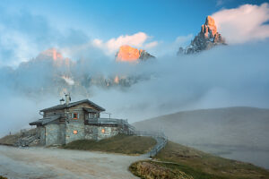 Baita Segantini surrounded by evening mist as the last light of sunset colors the Pale di San Martino peaks. Primiero San Martino di Castrozza, Trento province, Trentino, Italy Baita Segantini surrounded by evening mist as the last light of sunset colors the Pale di San Martino peaks. Primiero San Martino di Castrozza, Trento province, Trentino, Italy