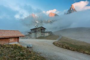 Baita Segantini surrounded by evening mist as the last light of sunset colors the Pale di San Martino peaks. Primiero San Martino di Castrozza, Trento province, Trentino, Italy Baita Segantini surrounded by evening mist as the last light of sunset colors the Pale di San Martino peaks. Primiero San Martino di Castrozza, Trento province, Trentino, Italy