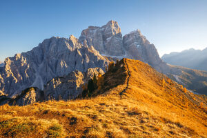Golden autumn light on the ridge trail of Col de la Puina facing Monte Pelmo at sunset. Val Fiorentina, Borca di Cadore, Belluno province, Veneto, Italy Golden autumn light on the ridge trail of Col de la Puina facing Monte Pelmo at sunset. Val Fiorentina, Borca di Cadore, Belluno province, Veneto, Italy