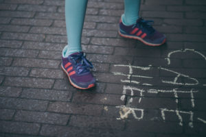 legs of a little girl stepping on some bricks floor with colorful sneakers 
