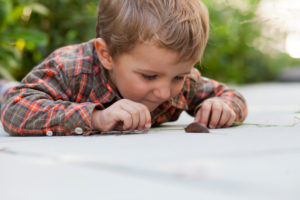 Boy playing with a slug on the ground Boy playing with a slug on the ground