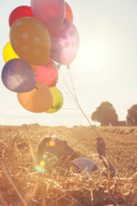 Young woman with colorful air balloons in a mowed grain field Young woman with colorful air balloons in a mowed grain field