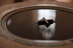 Kreuz im Weihwasserbecken, Kirchenfenster spiegelt sich im Wasser Kreuz im Weihwasserbecken, Kirchenfenster spiegelt sich im Wasser