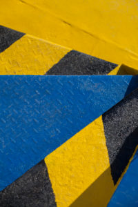 brightly colored metal stair steps on a ferry, color contrast yellow blue black, view downstairs brightly colored metal stair steps on a ferry, color contrast yellow blue black, view downstairs