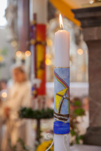 Candle for communion and paschal candle at Communion celebration in church