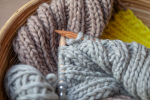 Knitting with fluffy wool and thick knitting needles in basket, earth tones Knitting with fluffy wool and thick knitting needles in basket, earth tones