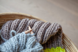 Knitting with fluffy wool and thick knitting needles in basket, earth tones Knitting with fluffy wool and thick knitting needles in basket, earth tones